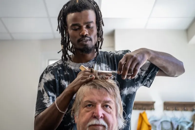 Coiffeur coupant les cheveux d'un client dans un salon lumineux